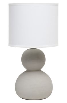 a lamp that is sitting on top of a white base with a light shade over it