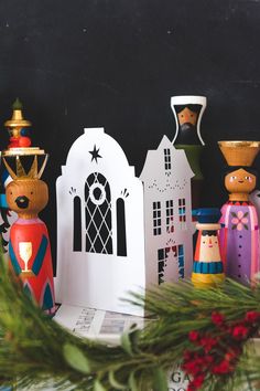 an assortment of colorful wooden figurines sitting on top of a table next to a christmas tree