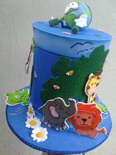 a blue cake with animals and plants on it's top, sitting on a table