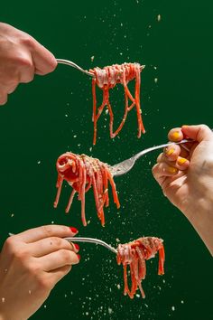 three people are eating spaghetti with red sauce on them and sprinkled with parmesan cheese