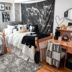 a bedroom decorated in black and white with an artistic wall hanging above the bed,