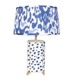 a blue and white lamp on a table with a shade over it's head