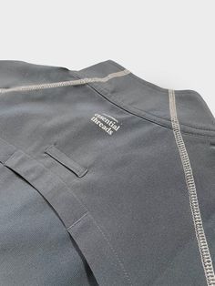 the back view of a gray shirt with white trimmings and an open pocket