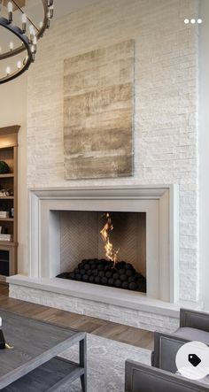 a living room filled with furniture and a fire place under a chandelier hanging from the ceiling