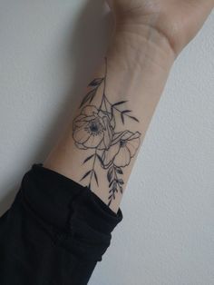 a woman's arm with a flower tattoo on the left side of her wrist