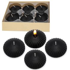 six black tealight candles in a cardboard box next to it's packaging and its contents