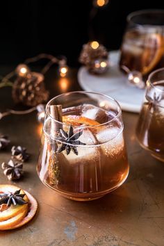 two glasses filled with drinks sitting on top of a table next to cookies and christmas lights