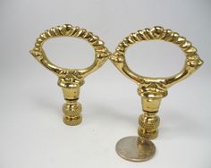 two gold candlesticks sitting on top of a white table next to a penny