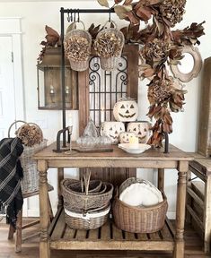 a wooden table topped with baskets filled with pumpkins and other fall decorating items