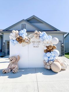 a teddy bear and balloon arch in front of a house