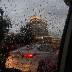 rain drops on the windshield of a car as it drives down a street in front of a building