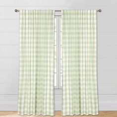 the green and white checkered curtains are hanging in front of a window with wood flooring