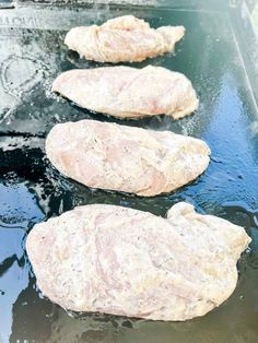 three raw meats are being cooked on the grill