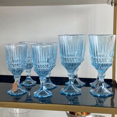 five blue glass goblets are lined up on a table