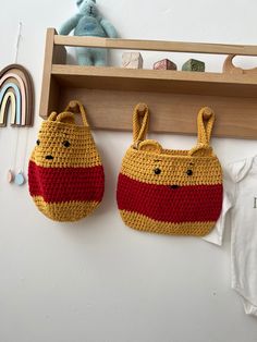 two crocheted purses hanging on the wall next to a baby's t - shirt