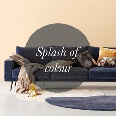 a blue couch sitting on top of a white floor next to a rug and pillows