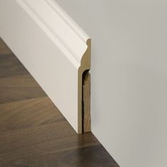 the corner of a white wall with a wooden door handle on it's side