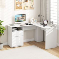 a white desk with a computer on it in a room next to a potted plant