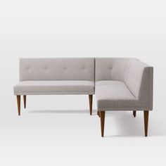 a gray couch with a white back and arm rest sitting next to each other in front of a white wall