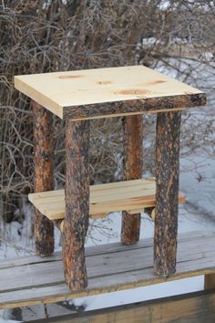 a wooden bench sitting on top of a snow covered ground in front of some trees