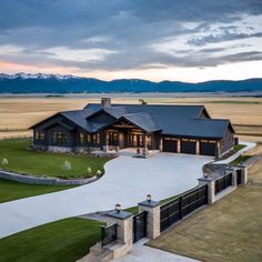 an aerial view of a large home in the middle of a field with mountains in the background