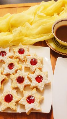 small cookies with jam on them sit on a plate next to a cup of coffee