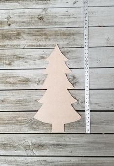 a wooden cutout of a christmas tree next to a ruler on a wood background