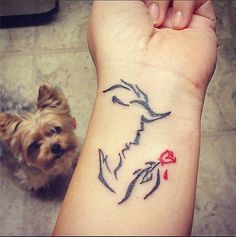 a small tattoo on the wrist of a woman with a dog sitting next to her