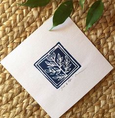 a piece of paper with a plant on it sitting on a woven mat next to some leaves