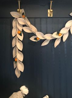 two stuffed animals sitting next to each other in front of a wall with leaves and oranges on it