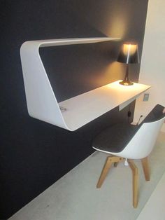 a desk with a chair underneath it and a lamp on the wall next to it