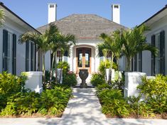 a house with palm trees in front of it and an entrance way to the home