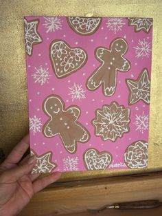 a hand holding up a piece of paper with gingerbreads and snowflakes on it