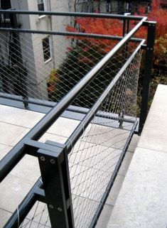 a metal fence on top of a building next to a tree and bushes in the background