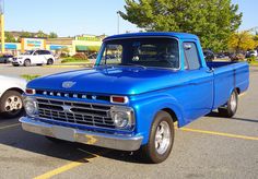 an old blue pickup truck parked in a parking lot