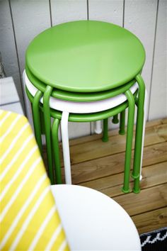 three green and white stools sitting on top of a wooden floor