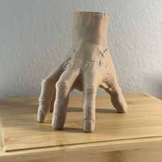 a clay hand sitting on top of a wooden table