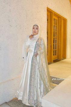 a woman wearing a white dress and veil standing in front of a door with her hands on her hips