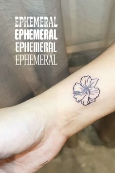 a small flower tattoo on the left inner arm and wrist is shown in black ink