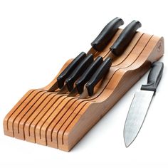 a knife holder with knives in it on a white surface and a wooden block holding several knives