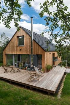 a wooden deck in front of a house with chairs and tables on the outside patio