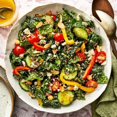 a white bowl filled with salad next to silverware and utensils on a table