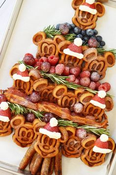 A delicious Christmas charcuterie board made out of Mickey shaped gingerbread waffles, applewood smoked bacon, strawberry santa hats, fresh berries and a tree trunk made out of sausage links Mickey Waffle, Mickey Waffles, Snack Boards, Charcuterie Inspiration, Mickey Christmas, Christmas Brunch, Christmas Breakfast, Christmas Party Food, Christmas Snacks