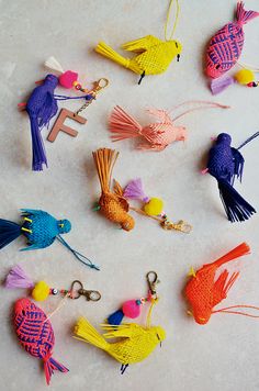 many different colored fish shaped keychains on a white surface with yellow, pink, and blue tassels