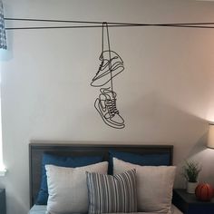 a bed room with a neatly made bed and a wall hanging shoe prints on the wall