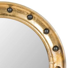 a round mirror with metal rivets on the edges and black beads around it