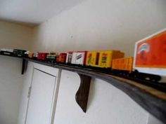 a toy train set on top of a shelf next to a white refrigerator freezer