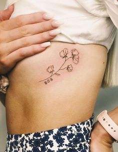 a woman's stomach with a small flower tattoo on her side ribcage