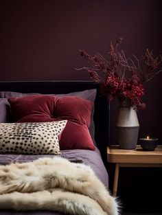 a bed with pillows and blankets on top of it next to a table with flowers