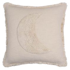 a white pillow with a crescent embroidered on the front and fringe trim around the edges